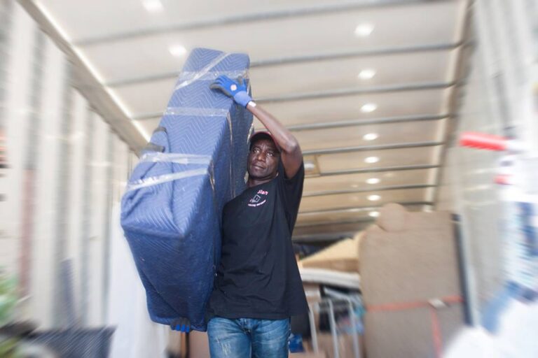 A team member of Canadian moving service in black shirt carried a box