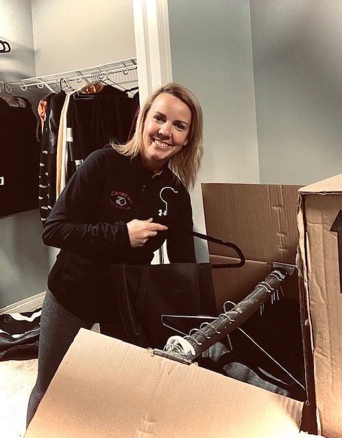 A woman is in wardrobe holding a hanger