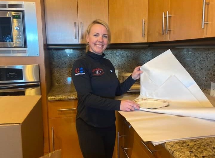 A woman is in kitchen holding a white paper